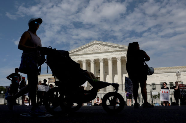 A woman pushes a stroller past a protest by abortion rights activists outside the United States Supreme Court in Washington, U.S., June 27, 2022. REUTERS/Evelyn Hockstein