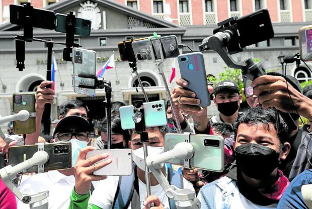 Crowd with cellphones outside the Comelec office in Intramuros. STORY: Accrediting vloggers a Palace media priority