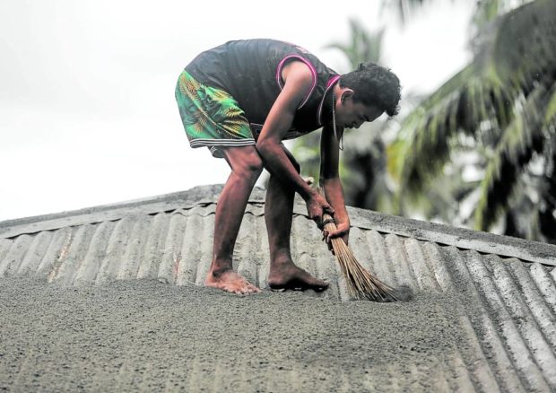 A resident of Puting Sapa village in Juban, Sorsogon, starts clearing ash that accumulated on his roof on Sunday afternoon, a few hours after the eruption of Mt. Bulusan. STORY: Bulusan calmer but Phivolcs says another eruption possible