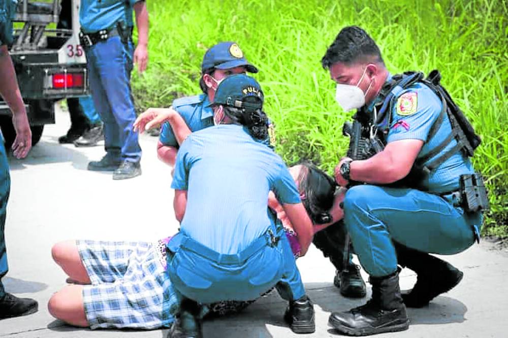 PASSED OUT Police officers assist a female who apparently passed out during the tension-filled arrest of 91 individuals in a disputed land reform property inTinang village, Concepcion, Tarlac on Thursday. PHOTO COURTESY OF THE TARLAC PROVINCIAL POLICE OFFICE robredo farmers