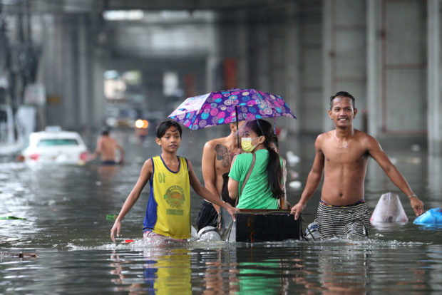 Residents wade at the floods on Araneta Avenue in Barangay Tatalon, Quezon City