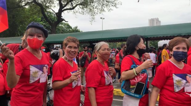Madonna Merveille, 65, and Precy Vizcarra, 68, along with their companions, wait in line outside the Club Intramuros Golf Course to witness Marcos Jr.'s inauguration. 