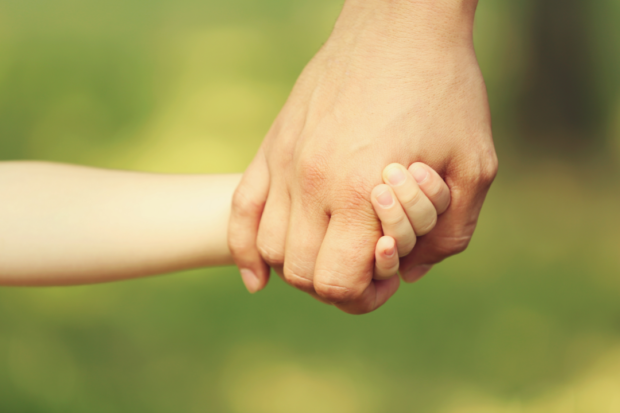 Adult hand holding child hand. STORY: Solo parents get P1,000 monthly, more perks under new law