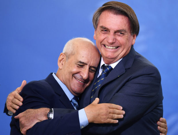 In this file photo taken on February 23, 2022, Brazilian President Jair Bolsonaro (R) hugs the General Secretary of Presidency Luiz Ramos during the launching ceremony of the National Identity Card, at Planalto Palace in Brasilia. - The Secretary General of the Brazilian Presidency, Luiz Ramos, during an interview with AFP in June 2022, predicted a "normal" presidential election in October, despite the defiant statements of President Jair Bolsonaro, but said he fears the action of "radicals" on the side of leftist rival Luiz Inacio Lula de Silva. (Photo by EVARISTO SA / AFP)