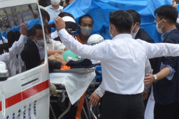 Former Japanese prime minister Shinzo Abe (C) is transported into an ambulance near Yamato Saidaiji Station after being shot in the city of Nara on July 8, 2022. - Shinzo Abe was shot at a campaign event on July 8, a government spokesman said, as local media reported the nation's longest-serving premier was showing no vital signs. (Photo by Yomiuri Shimbun / AFP) / Japan OUT / NO ARCHIVES