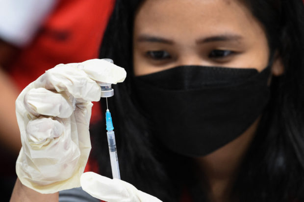 A medical worker prepares the Pfizer-BioNtech Covid-19 vaccine for children aged 5-11 at a gym in San Juan City, suburban Manila on February 7, 2022.