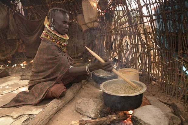Longole Lotak, boils wild fruits locally known as "edung", in her makeshift house at Parapul village, in the Loiyangalani area where families affected by the prolonged drought live, in Marsabit on July 11, 2022. 