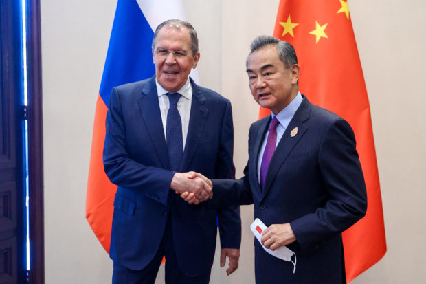 Russian Foreign Minister Sergei Lavrov and Chinese Foreign Minister Wang Yi shake hands as they meet in Indonesia and Wang Yi says 