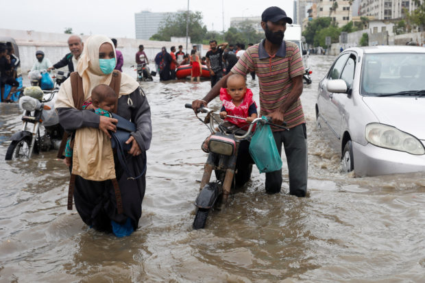 A family wades through a flooded road during the monsoon season in Karachi, Pakistan July 9, 2022. REUTERS/Akhtar Soomro