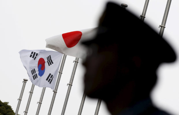 A police officer stands guard near Japan and South Korea national flags at hotel, where South Korean embassy in Japan is holding the reception to mark the 50th anniversary of normalisation of ties between Seoul and Tokyo, in Tokyo  June 22, 2015. REUTERS/Toru Hanai/Files