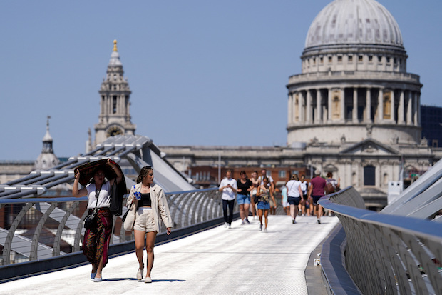 People cover themselves from the sun at Millennium Bridge in London. STORY: Britain boils in record temperature of 40°C