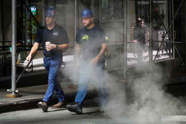 Workers walk through a cloud of steam during a heatwave in New York City, U.S., July 19, 2022.  REUTERS/Brendan McDermid