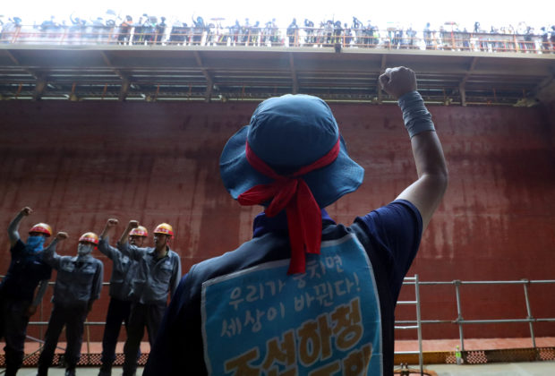 Members of the subcontractor union chant slogans on the floor of the occupied oil tanker during a strike at Daewoo Shipbuilding & Marine Engineering in Geoje, South Korea, July 19, 2022. The sign reads "We can't live like this". Yonhap via REUTERS