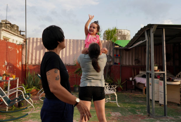 A couple, Gabriela Alfonso Perez, 23, and Ria Acosta, 27, plays in their garden with Ria's daughter Ivelle Acosta, 2, in Havana, Cuba, July 13, 2022. REUTERS/Alexandre Meneghini