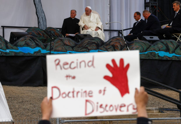 A person holds a protest sign as Pope Francis attends an event at Nakasuk School, in Iqaluit, Canada July 29, 2022. REUTERS/Guglielmo Mangiapane