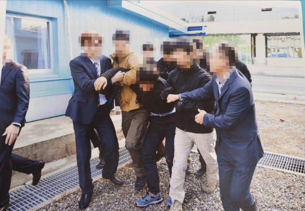n this photograph released by the Ministry of Unification, North Korean fishermen are apparently dragged by officials to be handed over to North Korea via the Military Demarcation Line.