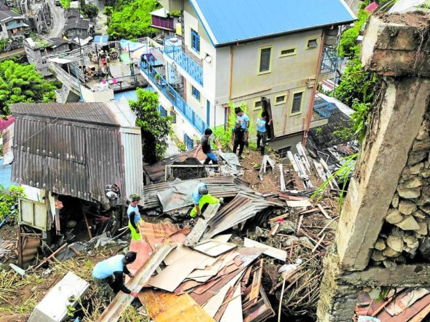 Policemen and disaster response personnel on Wednesday clear debris left by flash floods and landslides that hit houses and roads at Sitio Pangngat in Banaue, Ifugao.