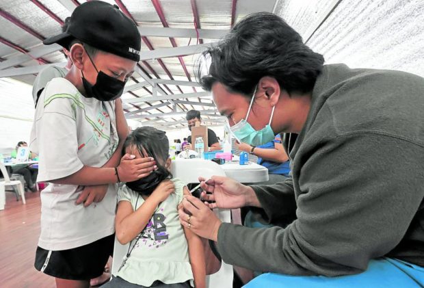 A boy stays by his younger sister’s side as the latter receives her COVID-19 vaccine shot at Marikina Sports Center in Marikina City on Monday. The city government is continuing its vaccination drive to cover children between 5 and 11 years old, especially with the resumption of in-person classes starting in August. STORY: DOH reports 44% surge in daily COVID-19 infections