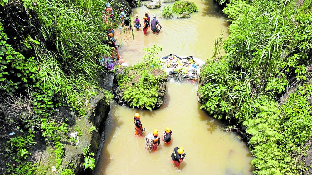 Rescuers search along a section of Imus River on Wednesday to find the bodies of seven teenagers after an old steel bridge collapsed