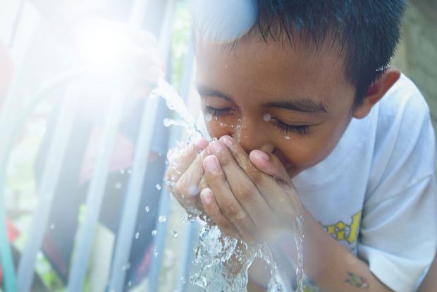 A child drinks water from a tap and Manila Water assures that the water being supplied to its customers is safe for drinking