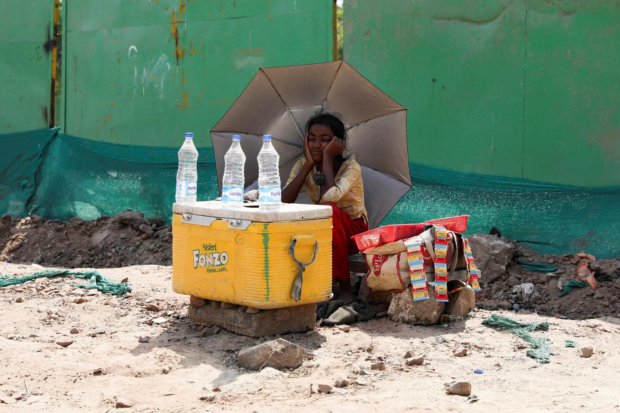 A girl selling water shielding herself from the sun in New Delhi