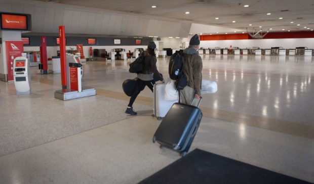 Travellers walk through a deserted Qantas terminal at Melbourne Airport on August 26, 2021 as Australian airline Qantas posted more than 1 billion USD in annual losses, after what it described as a "diabolical" year caused by pandemic travel restrictions.