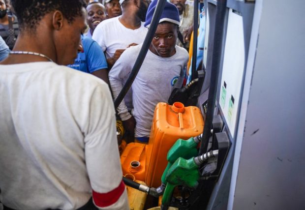 Haitians que to collect petrol at a gas station in Port-au-Prince on July 15, 2022. - 