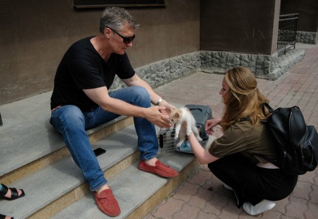A woman hands a kitten to Russian opposition figure and former mayor of Yekaterinburg Yevgeny Roizman at the entrance to his charity fund in the main Urals city of Yekaterinburg on July 15, 2022.