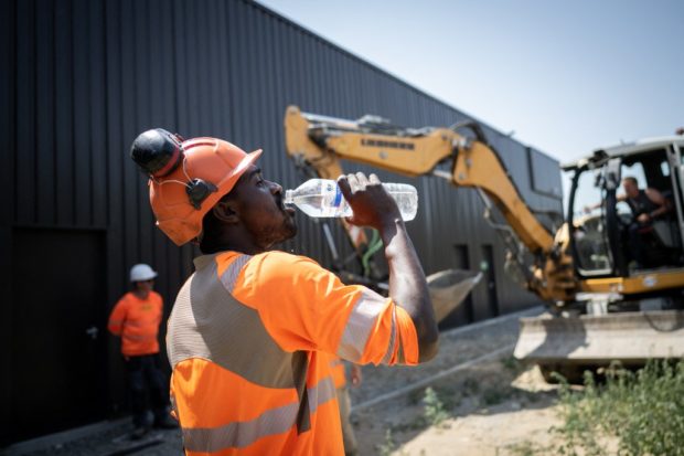 A worker drinks water in a construction site in Savenay, outside Nantes, on July 18, 2022, as a heatwave hits France. 