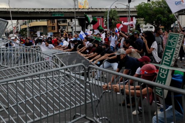 Protesters tear down a barrier during a march against the high cost of food and gasoline in Panama City, on July 12, 2022. 