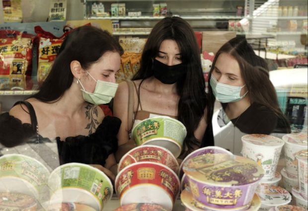 In this picture taken on June 22, 2022, Ukrainian students (L-R) Anna Fursyk, Karyna Myshnova and Alina Kuprii check instant noodles in a shop at Tunghai University in Taichung, central Taiwan. - 