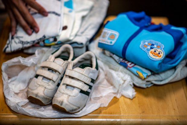 This picture taken on June 10, 2022 shows sweatshirts and a pair of white sneakers belonging to Koichi Miyatsu, items on him as a toddler when we was placed in a "baby hatch" where children can be left anonymously by desperate family, as he speaks during an interview with AFP in Kumamoto. 