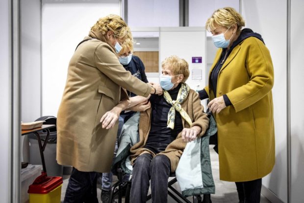 An employee of a Municipal Health Service (GGD in Dutch) injects a booster shot to an elderly woman at a vaccination centre in Utrecht, on November 19, 2021.