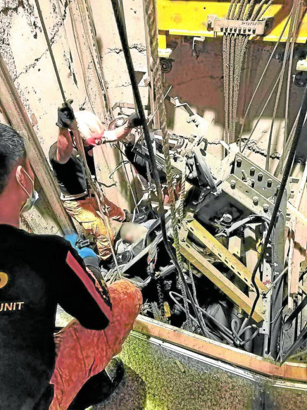 An elevator repairman looks at what remained of the elevator after it fell from the 38th floor to the ground; Burgundy Tower