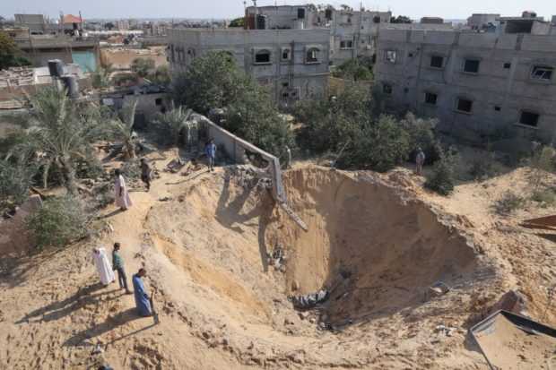 Palestinians inspect a crater following the latest three days of conflict with Israel ahead of a truce, in Rafah town in the southern Gaza Strip, on August 8, 2022. (Photo by SAID KHATIB / AFP)