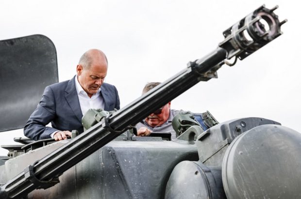 German Chancellor Olaf Scholz climbs with head of training at arms manufacturer Krauss-Maffei Juergen Schoch (R) on a German self-propelled anti-aircraft gun Flakpanzer Gepard during a visit of the training program for Ukrainian soldiers on the Gepard anti-aircraft tank in Putlos near Oldenburg, on August 25, 2022. - Scholz meets with soldiers and industrial trainers from the manufacturing company Krauss-Maffei Wegmann at the Putlos military training area in Schleswig-Holstein. (Photo by Axel Heimken / POOL / AFP)