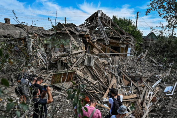 People stand next to a residential house destroyed by a Russian missile strike in the settlement of Kushuhum, as Russia's attack on Ukraine continues, in Zaporizhzhia region, Ukraine August 10, 2022.  REUTERS/Dmytro Smolienko