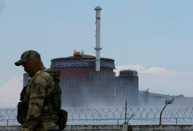 A serviceman with a Russian flag on his uniform stands guard near the Zaporizhzhia Nuclear Power Plant in the course of Ukraine-Russia conflict outside the Russian-controlled city of Enerhodar in the Zaporizhzhia region, Ukraine August 4, 2022. REUTERS/Alexander Ermochenko