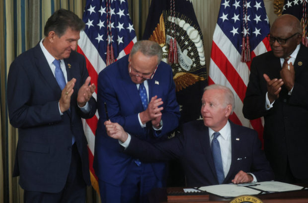 U.S. President Joe Biden holds out his pen to U.S. Senator Joe Manchin (D-WV) as Senate Majority Leader Chuck Schumer (D-NY) and U.S. House Majority Whip James Clyburn (D-SC) look on after Biden signed "The Inflation Reduction Act of 2022" into law during a ceremony in the State Dining Room of the White House in Washington, U.S. August 16, 2022. REUTERS/Leah Millis