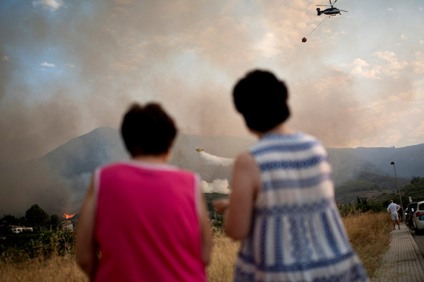 Women watch a plane drop water onto a wildfire near Pego, Spain, Aug. 16, 2022. STORY: Spanish crew's brush with death in raging Valencia wildfire