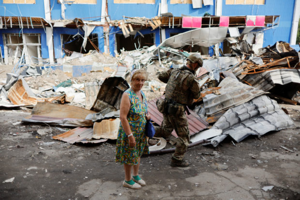 A woman stands next to a destroyed shopping center, as Russia's attack in Ukraine continues, in Bakhmut, Donetsk region, Ukraine August 21, 2022. REUTERS/Ammar Awad