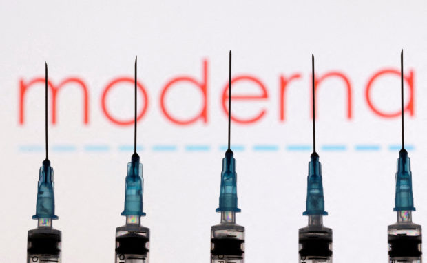 FILE PHOTO: Syringes with needles are seen in front of a displayed Moderna logo in this illustration taken November 27, 2021. REUTERS/Dado Ruvic/Illustration//