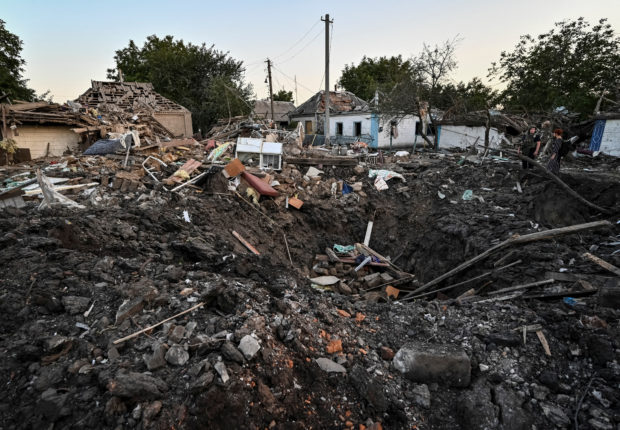 People stand next to a residential house destroyed by a Russian military strike, as Russia's attack on Ukraine continues, in Chaplyne, Dnipropetrovsk region, Ukraine August 24, 2022.  REUTERS/Dmytro Smolienko