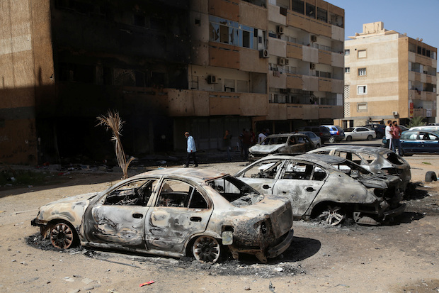 People gather next to burnt cars after yesterday's clashes in Tripoli. STORY: Tripoli calm, Libya riven after worst fighting in years