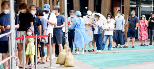 People wait in line to get COVID-19 tests at a local testing station in Songpa-gu, Seoul