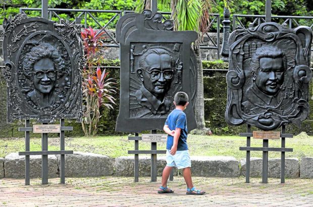 A boy looks at a row of metalwork depicting Presidents Corazon Aquino, Fidel Ramos and Joseph Estrada on display in Intramuros, Manila. Ramos, who died at 94 on July 31, will be accorded a state funeral on Tuesday at Libingan ng mga Bayani. STORY: Special Forces Regiment members pay tribute to FVR