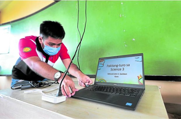 A teachers checks the laptop issued to him by the government as the units were allegedly overpriced but outdated