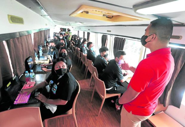 Students from the Smokey Mountain community in the Manila district of Tondo attend a “pilot” class session at a passenger bus converted into a roving classroom. This project by the Polytechnic University of the Philippines aims to promote tertiary education among young workers seeking to complete their schooling. STORY: PUP deploys ‘school bus’ to bring education on the road