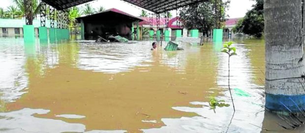 A teacher navigates through floodwater at Datu Udtog Matalam High School following the flash floods that hit the Maguindanao town of Pagalungan on Friday. STORY: Floods destroy school materials in Mindanao