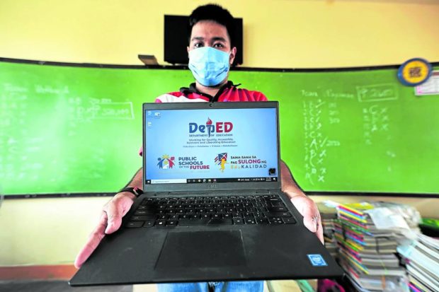 Teacher showing a DepEd laptop. STORY: PS-DBM to buy only ‘common-use’ items